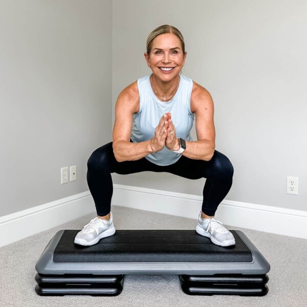 woman smiling doing step exercises on platform