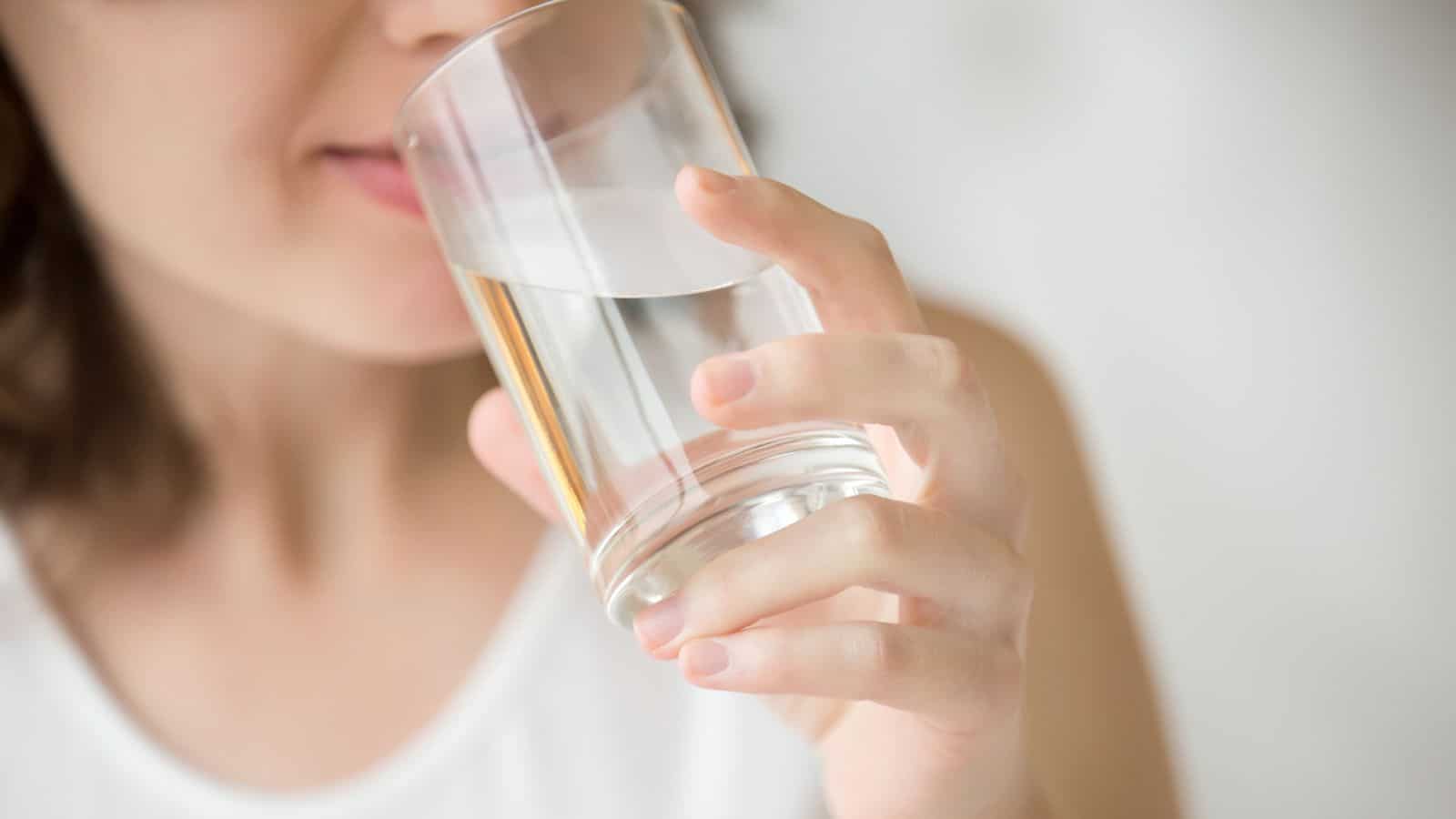 Close up of a woman drinking a glass of water.