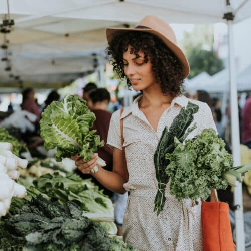 woman at farmers market holding kale
