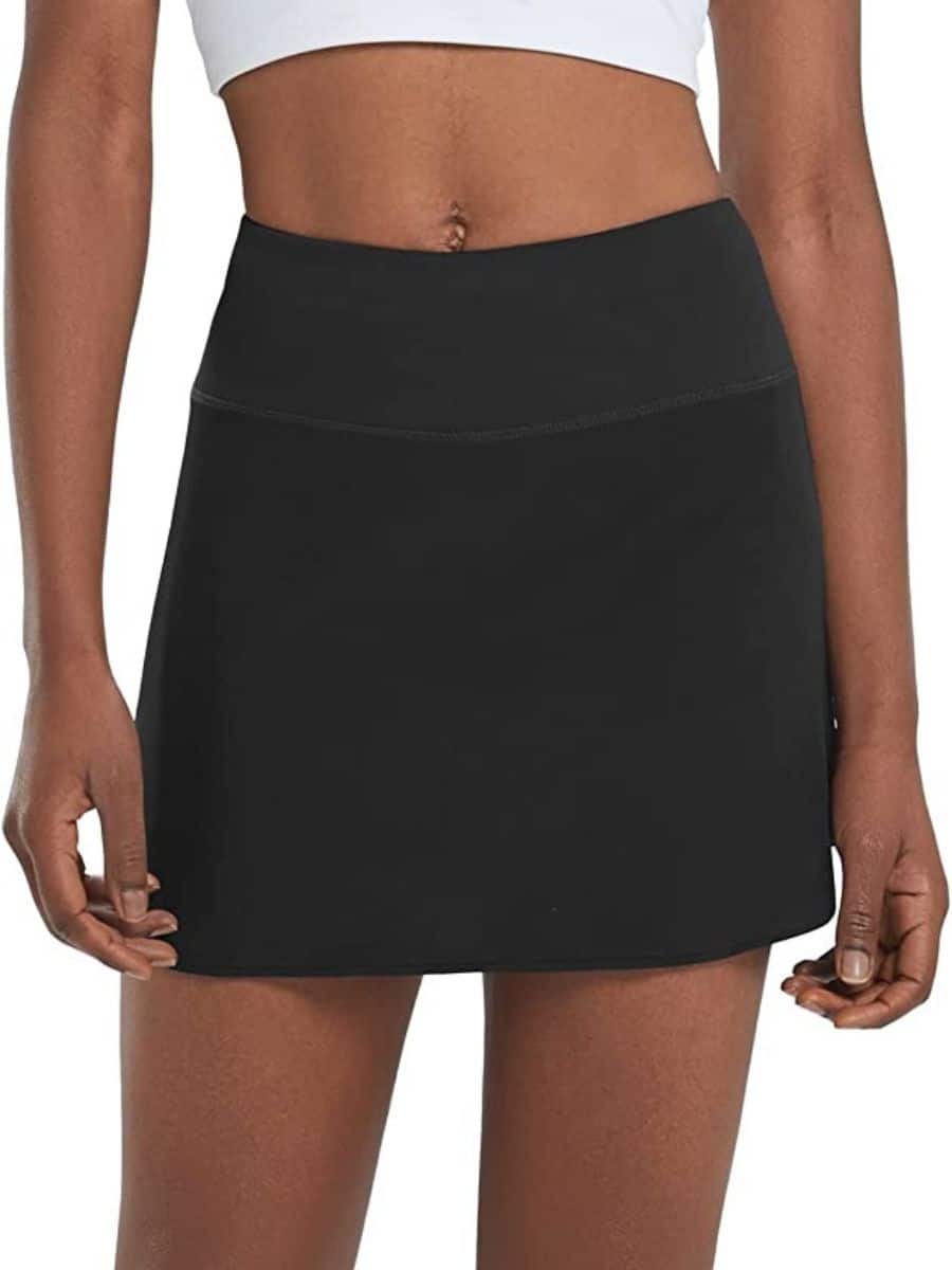 A person wearing a black BALEAF pleated tennis skirt.