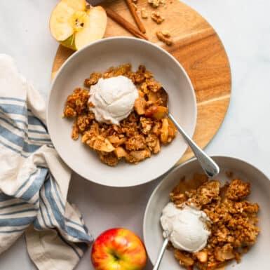 healthy apple crisp dished into a bowl with a scoop of ice cream.