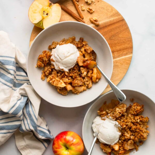 healthy apple crisp dished into a bowl with a scoop of ice cream.