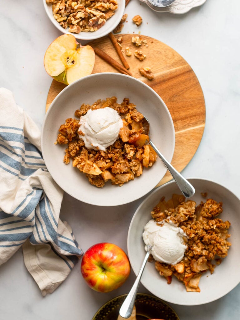 healthy apple crisp dished into a bowl with a scoop of ice cream.