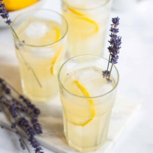 lavender lemonade in a tall glass with lemon slices, ice, and sprigs of fresh lavender.