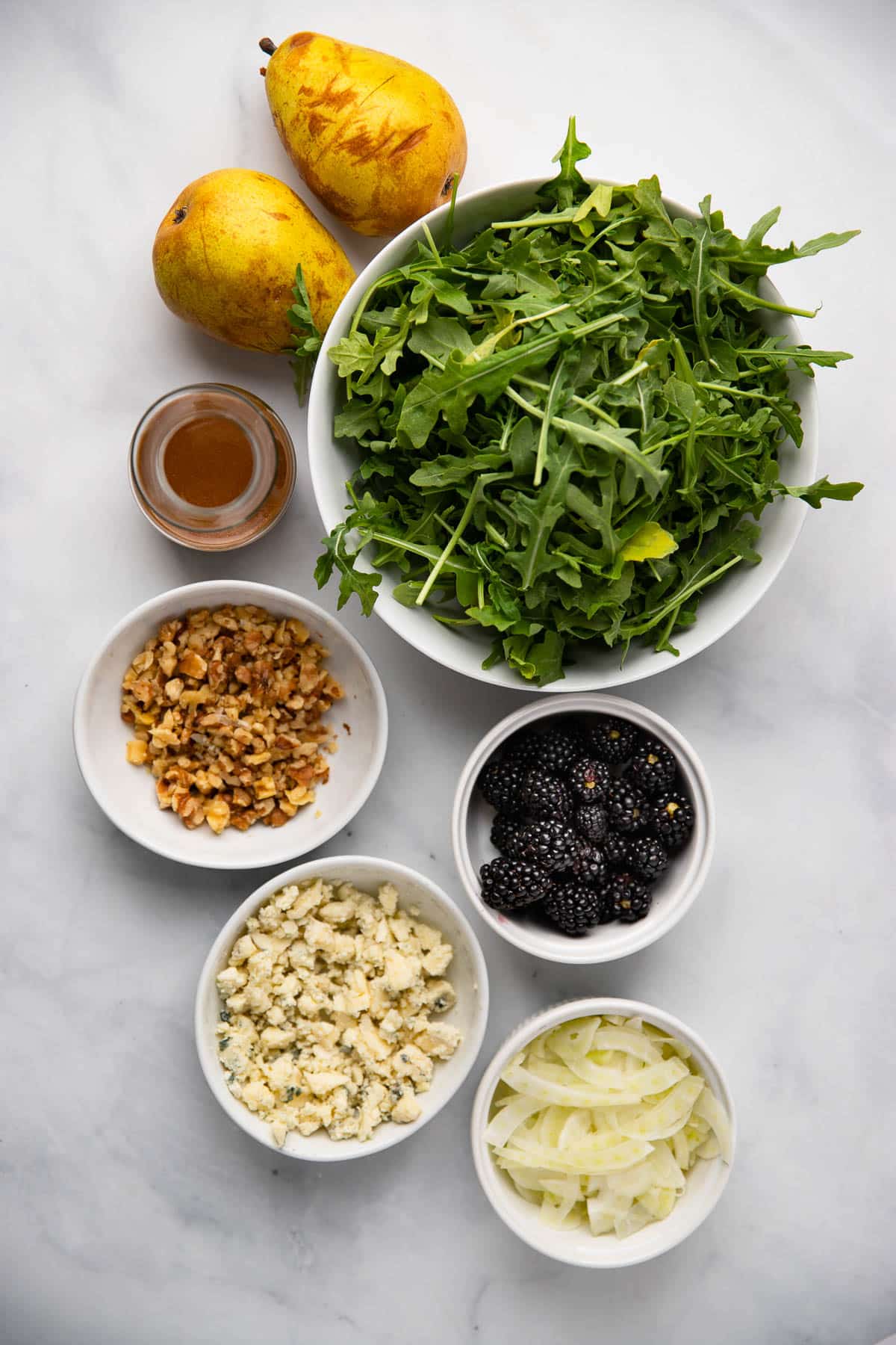 pear salad ingredients in small bowls on a white background.
