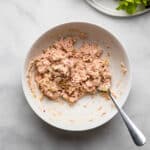 healthy tuna salad mixed together in a white bowl with a fork.