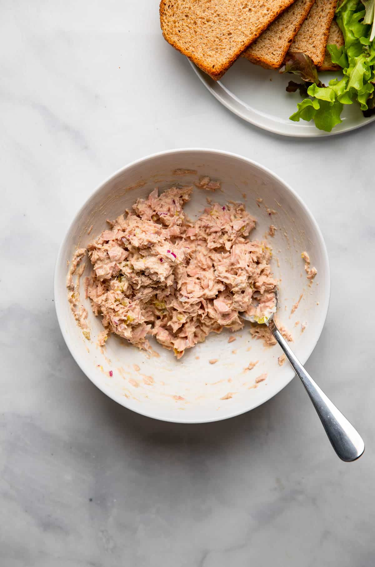 healthy tuna salad mixed together in a bowl with a spoon.