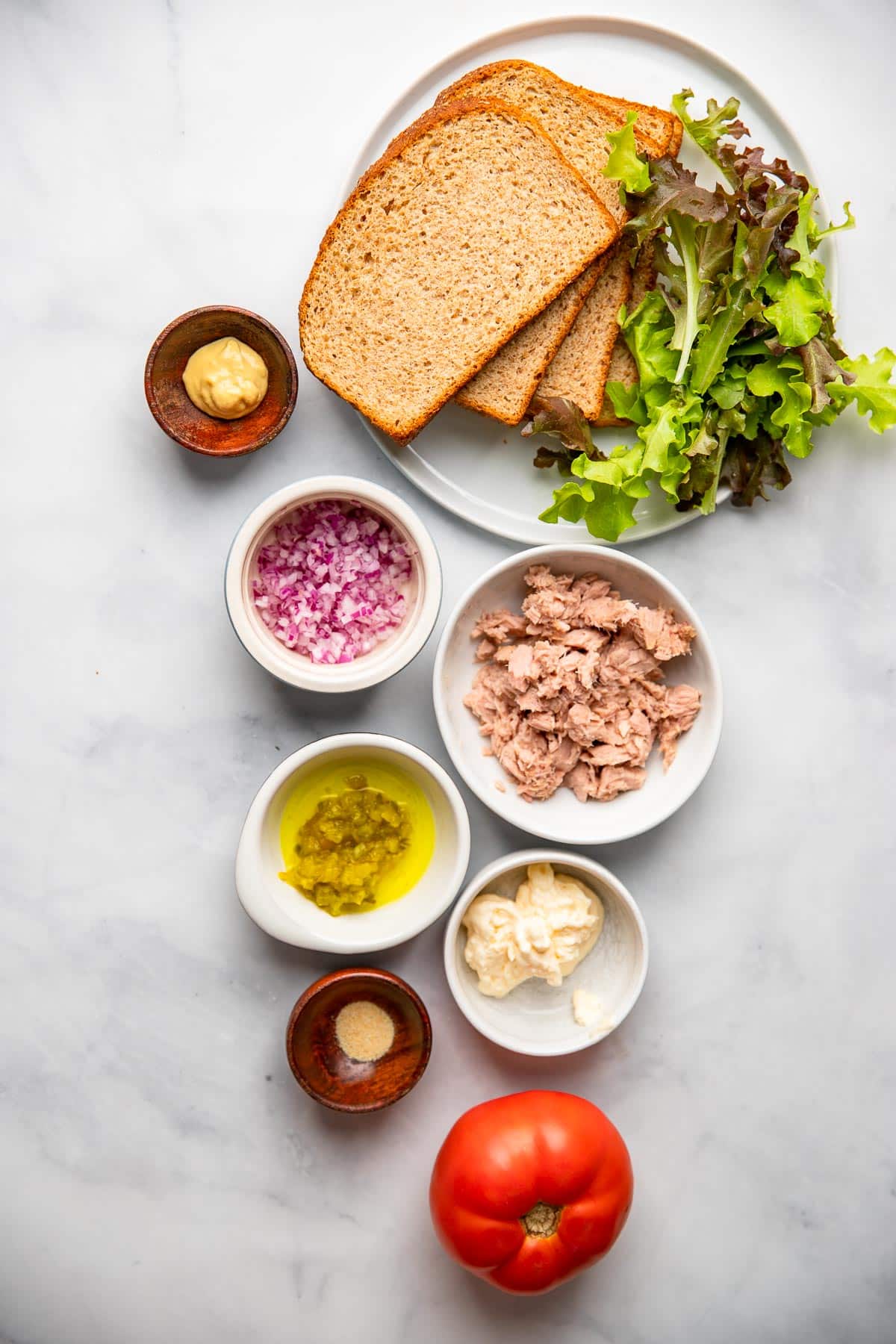 yellowfin tuna salad ingredients in small bowls on a white background.