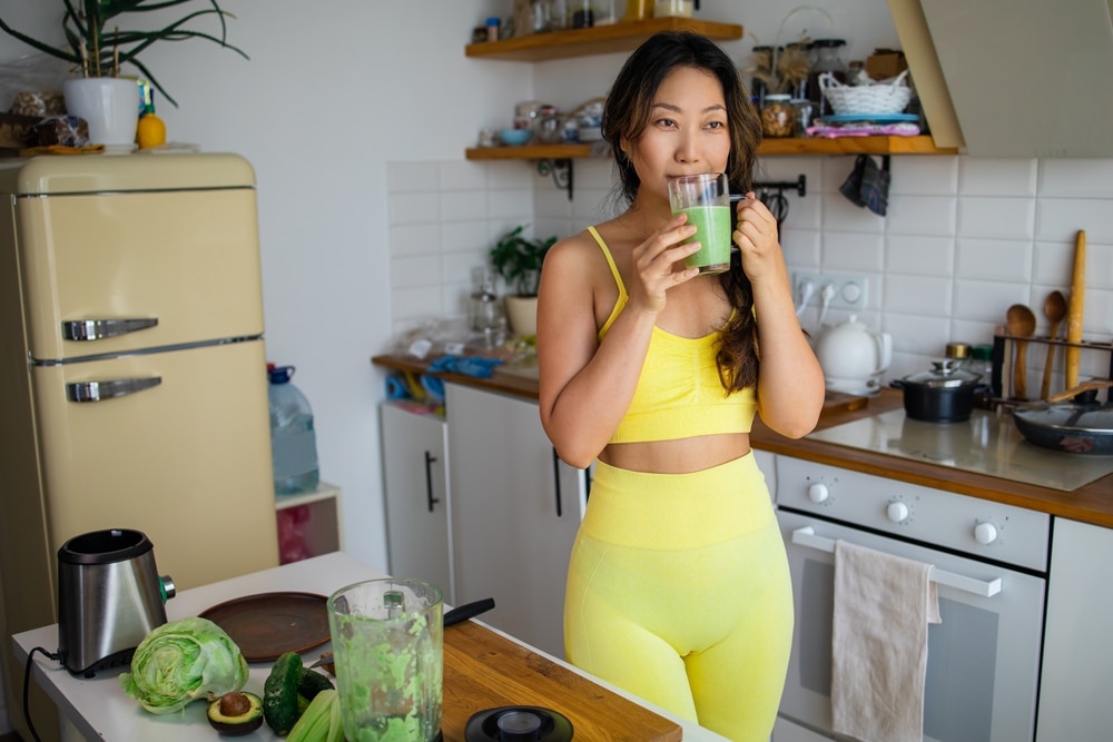 woman drinking celery in her kitchen