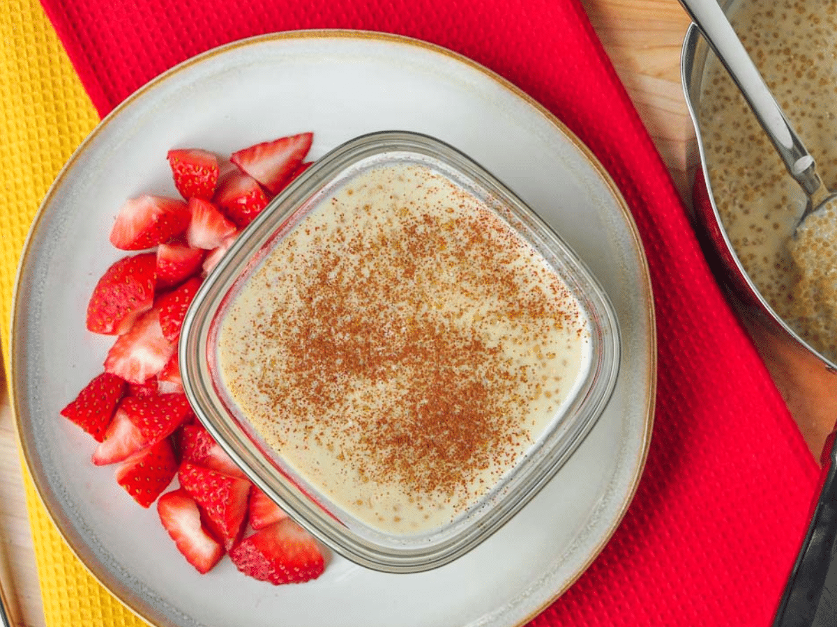 A bird's-eye view of a creamy quinoa pudding topped with cinnamon and surrounded with fresh-cut strawberries.