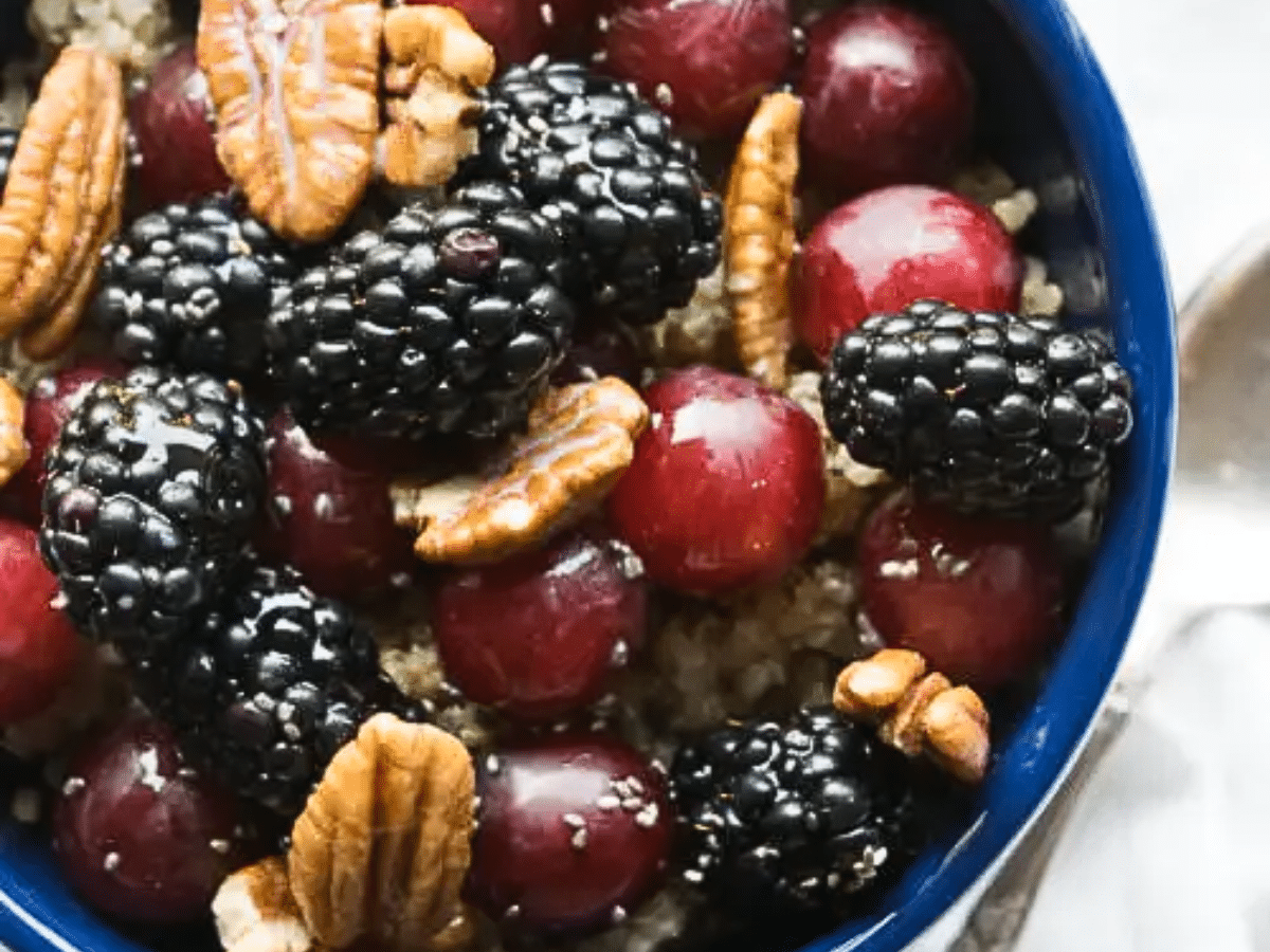 A quinoa breakfast bowl with blackberries, grapes, and nuts.