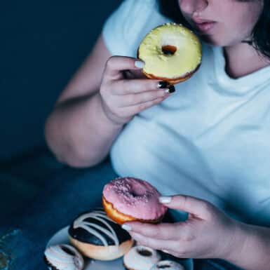 Woman in blue shirt eating a donut.