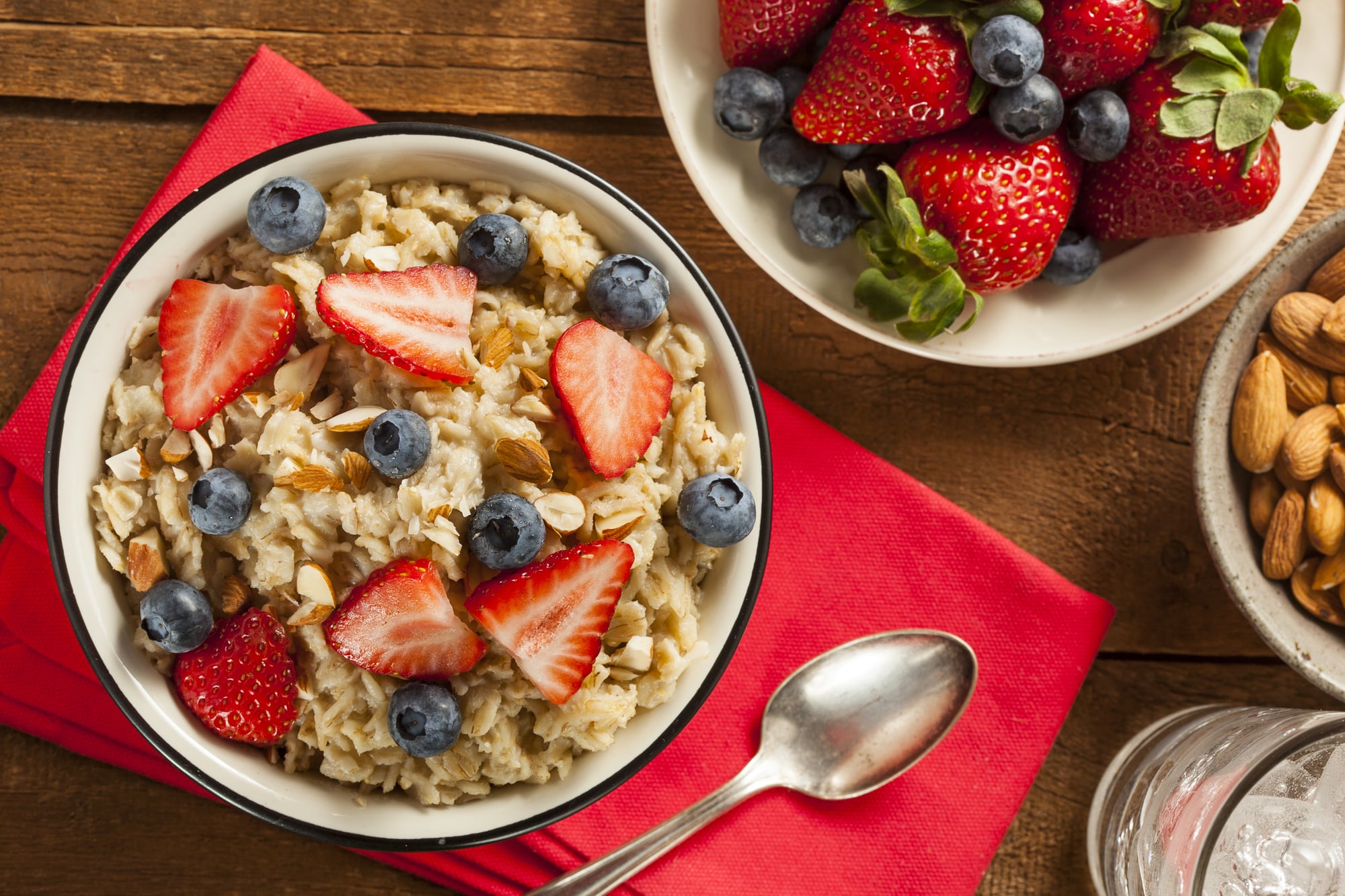 A vessel  of oatmeal topped with strawberries and blueberries.