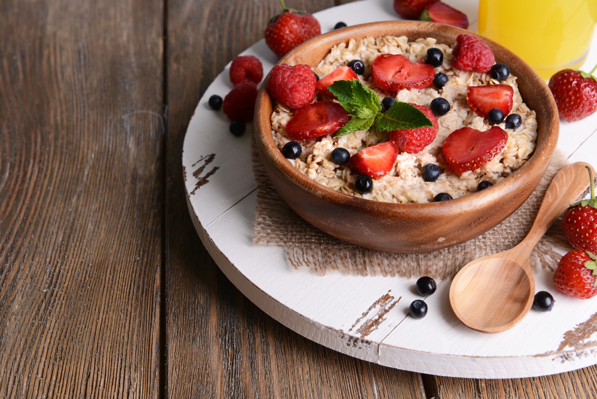 A close-up of a bowl of oatmeal with berries on a wooden table.