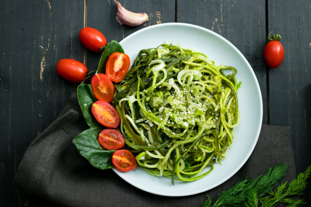 A plate of zucchini noodles with halved cherry tomatoes.