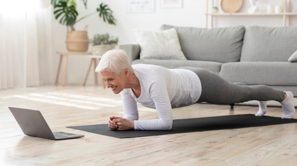 Senior woman doing a plank exercise at home.