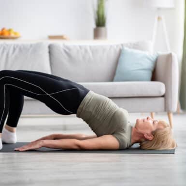 A woman doing a bridge exercise in her living room.