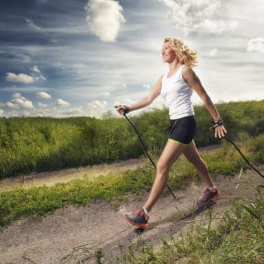 A woman nordic walking outdoors with trekking poles.