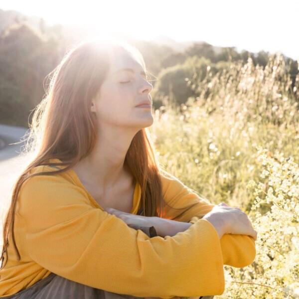 woman sitting in grass with sun on face