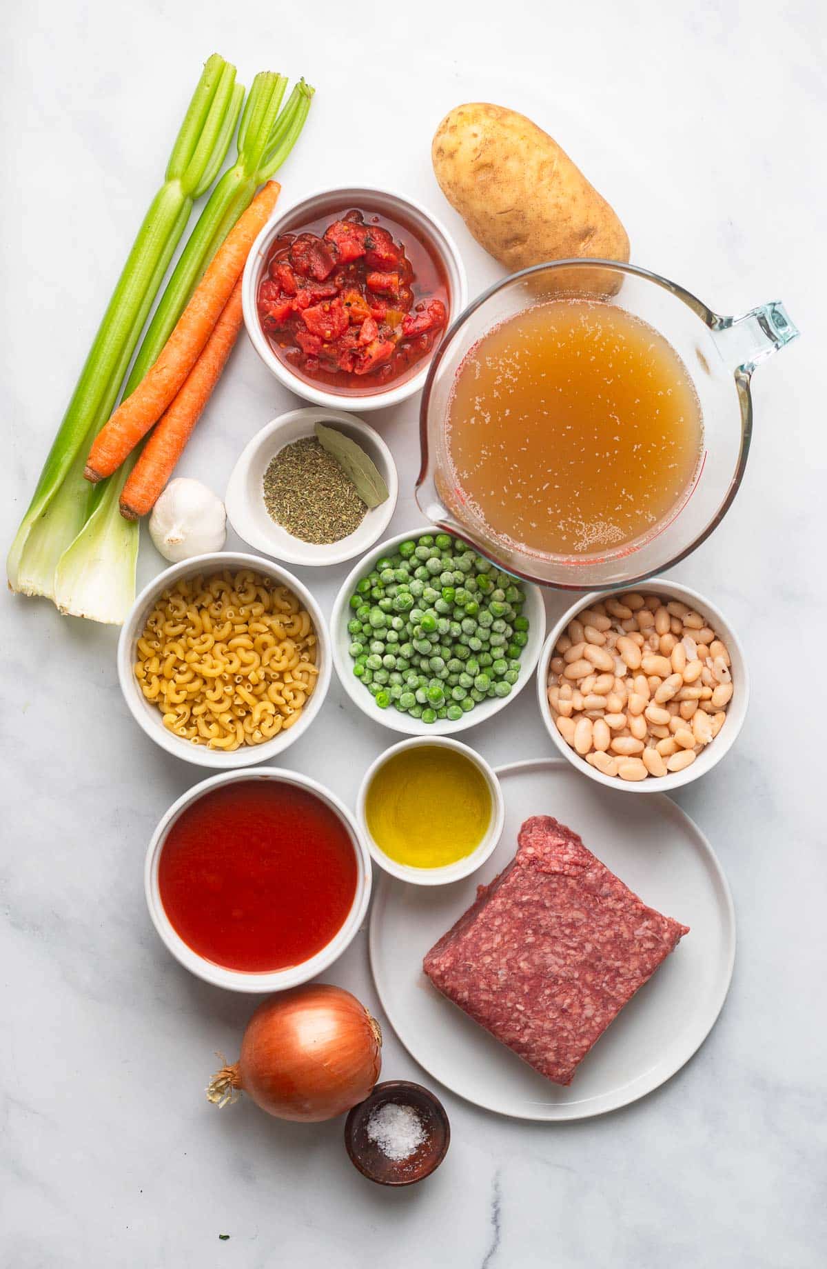 top view of raw ingredients for making healthy hamburger soup on a white counter