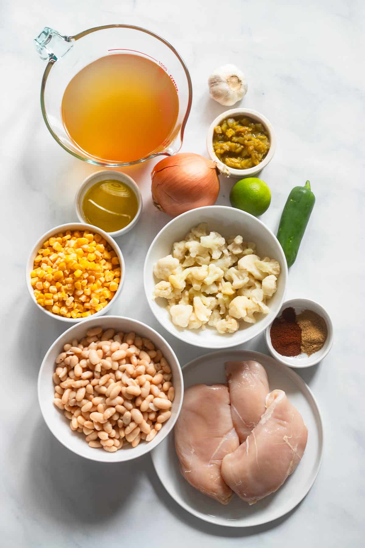 top view of raw ingredients for healthy white chicken chili on white countertop