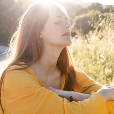 woman sitting in grass with sun on face