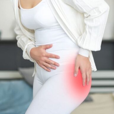 A woman dressed in all white with her hip pain highlighted in red.
