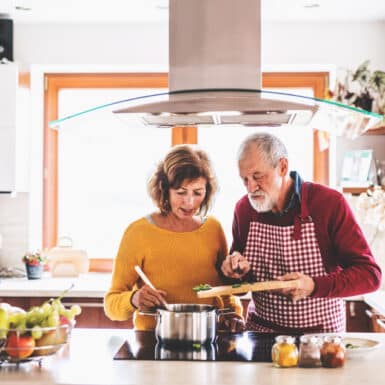 An older couple cooking together in the kitchen.