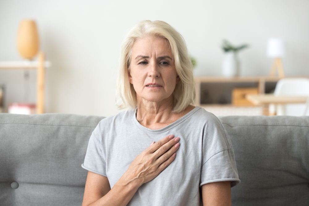 Uncomfortable woman touching an ache in her chest.