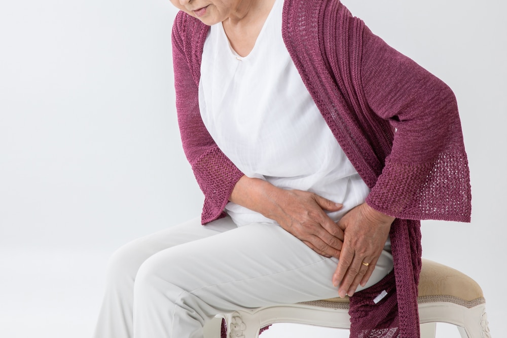 An older woman sitting on a chair with hip pain.