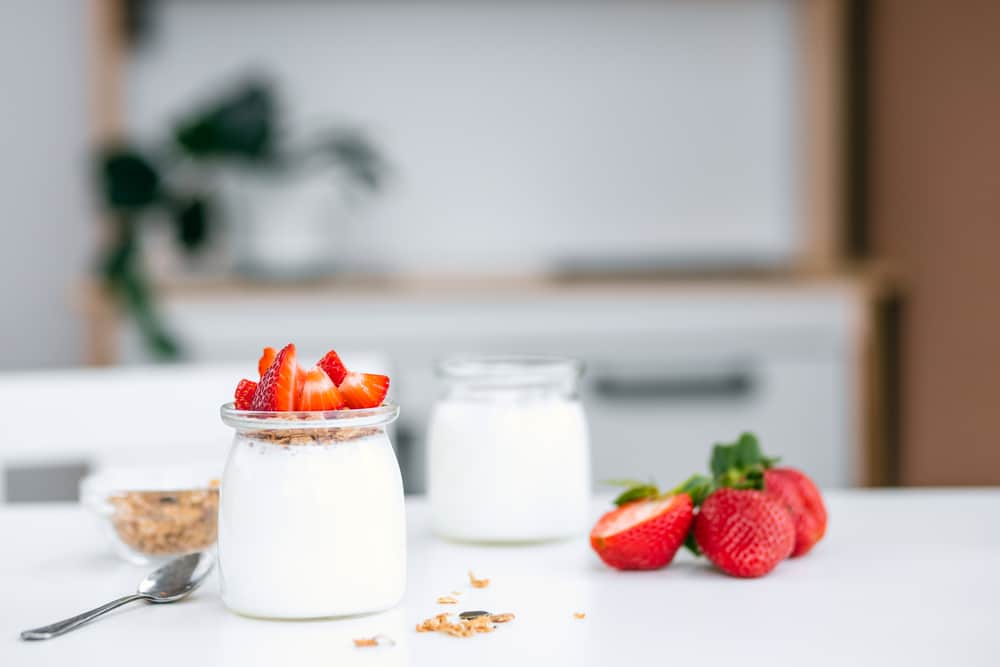 Greek yogurt in a glass jar topped with strawberries.