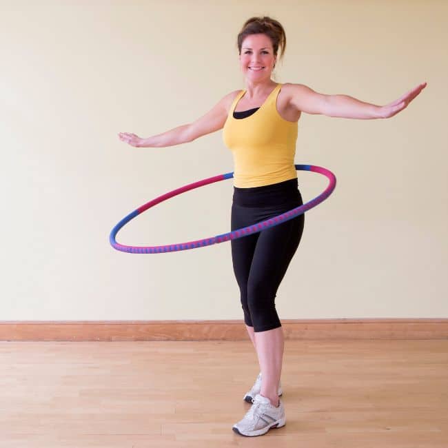 woman standing with weighted hula hoop swinging around her waist