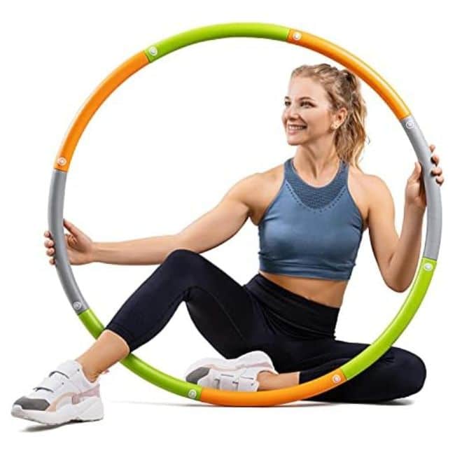 woman holding green and orange weighted hula hoop