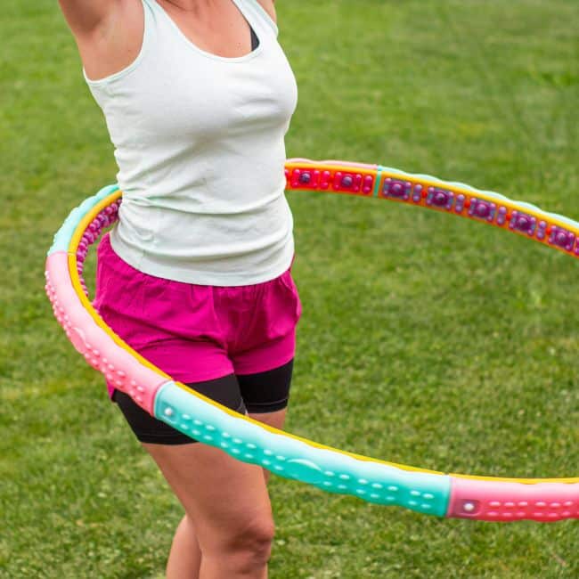 woman outside in grass with weighted hula hoop around her waist