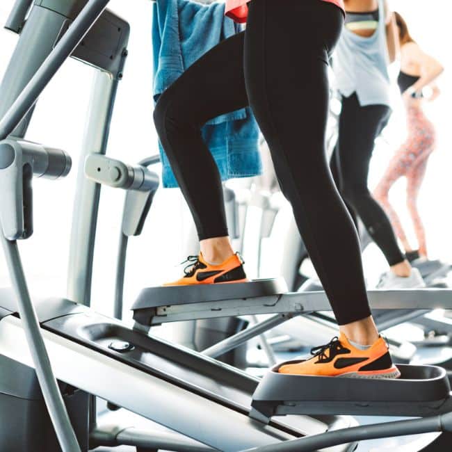 woman with orange shoes using elliptical machine at gym, elliptical vs treadmill