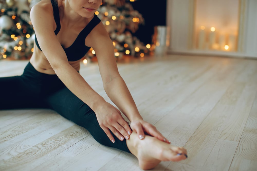 woman exercising during the holidays by christmas tree