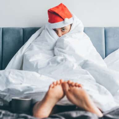 woman with holiday hangover on couch with santa hat