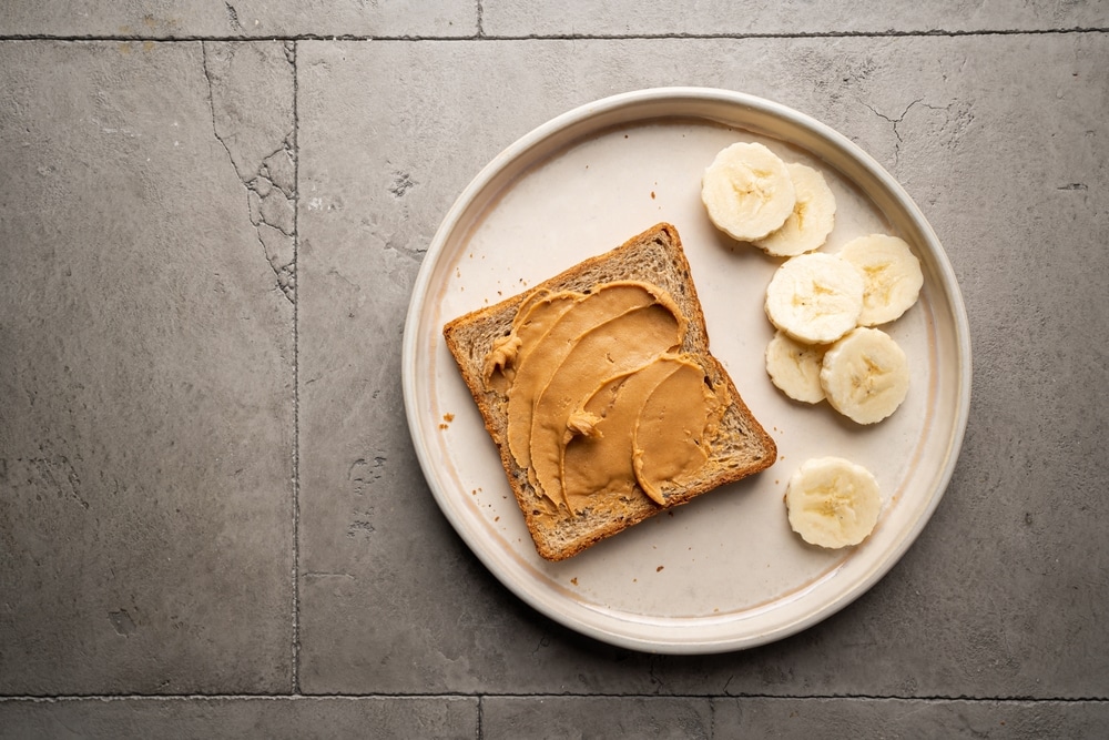 Overhead view of peanut butter toast and banana slices on a plate.