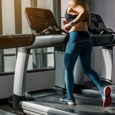 A woman running on a treadmill at the gym.