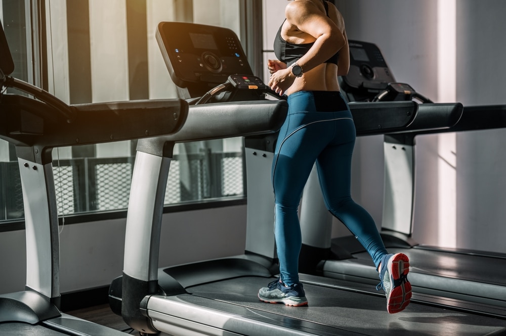 A woman running on a treadmill at the gym.