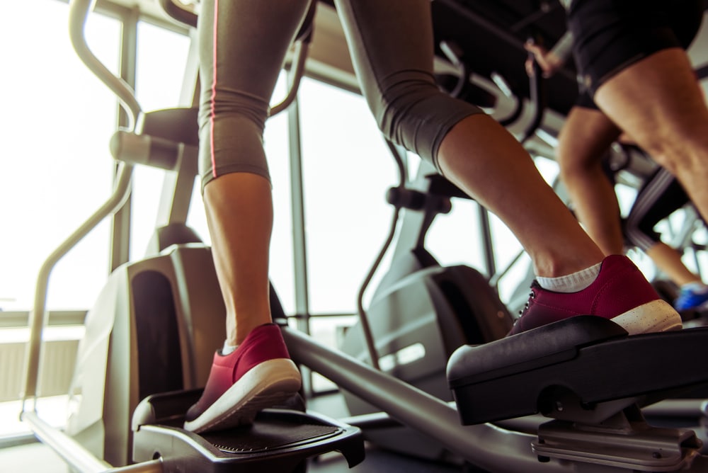 Close up of a woman's feet exercising on an elliptical machine.