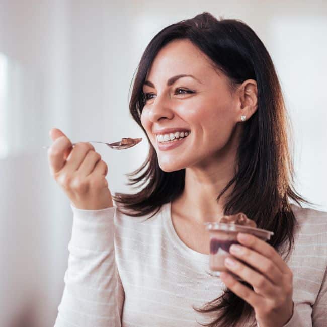 woman smiling eating chocolate pudding dessert