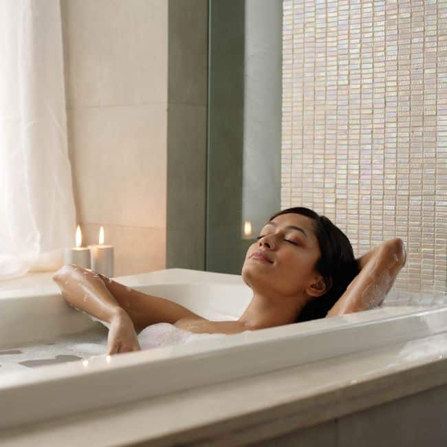 woman relaxing in bathtub with eyes closed