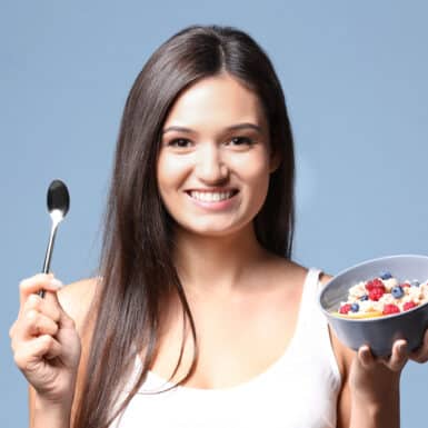 happy woman holding bowl of oatmeal and spoon smiling