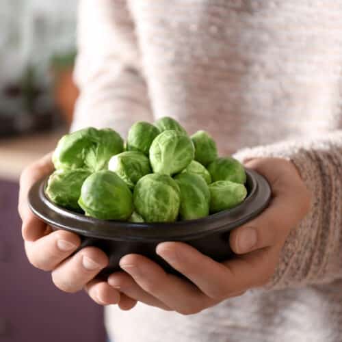 woman holding bowl of brussels sprouts