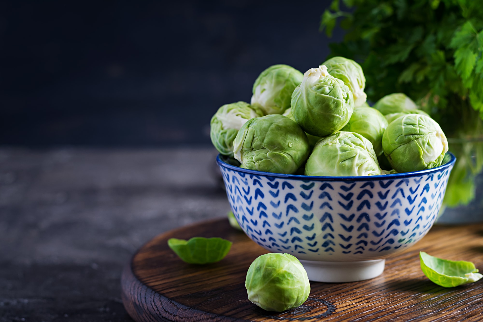 bowl of brussels sprouts in blue bowl on dark background