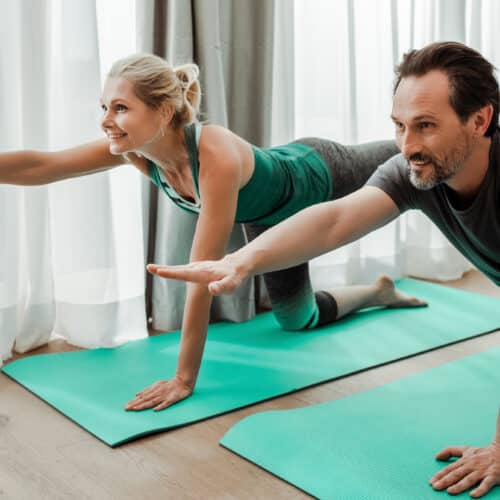 man and woman doing core workout together on teal workout mats