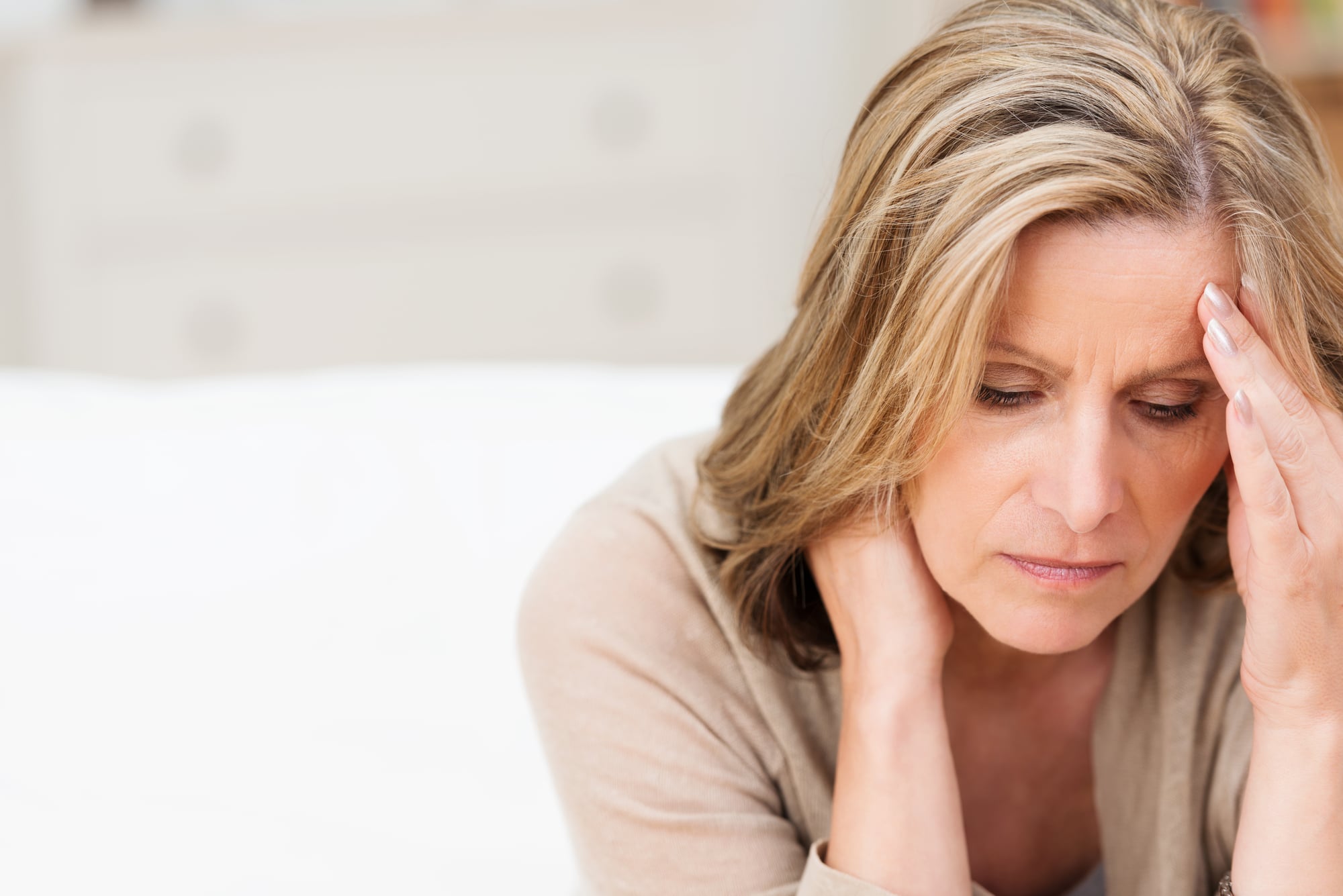 woman looking down holding head depressed