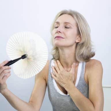 woman in perimenopause fanning herself through hot flash