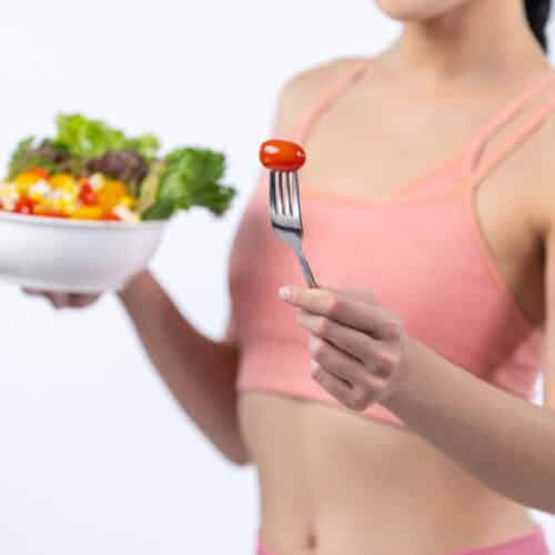 woman in sports bra holding healthy post workout salad meal
